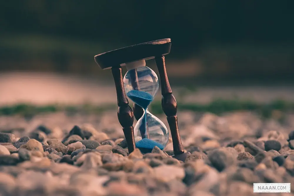 selective focus photo of brown and blue hourglass on stones