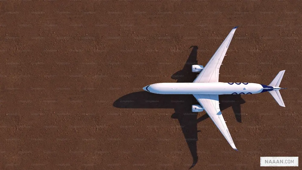 a white airplane flying over a brown ground