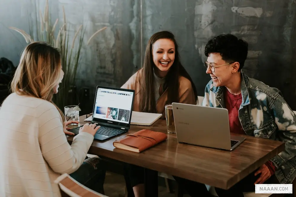 three people sitting in front of table laughing together