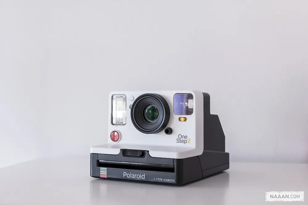 white and black Polaroid One Step 2 instant camera on white board